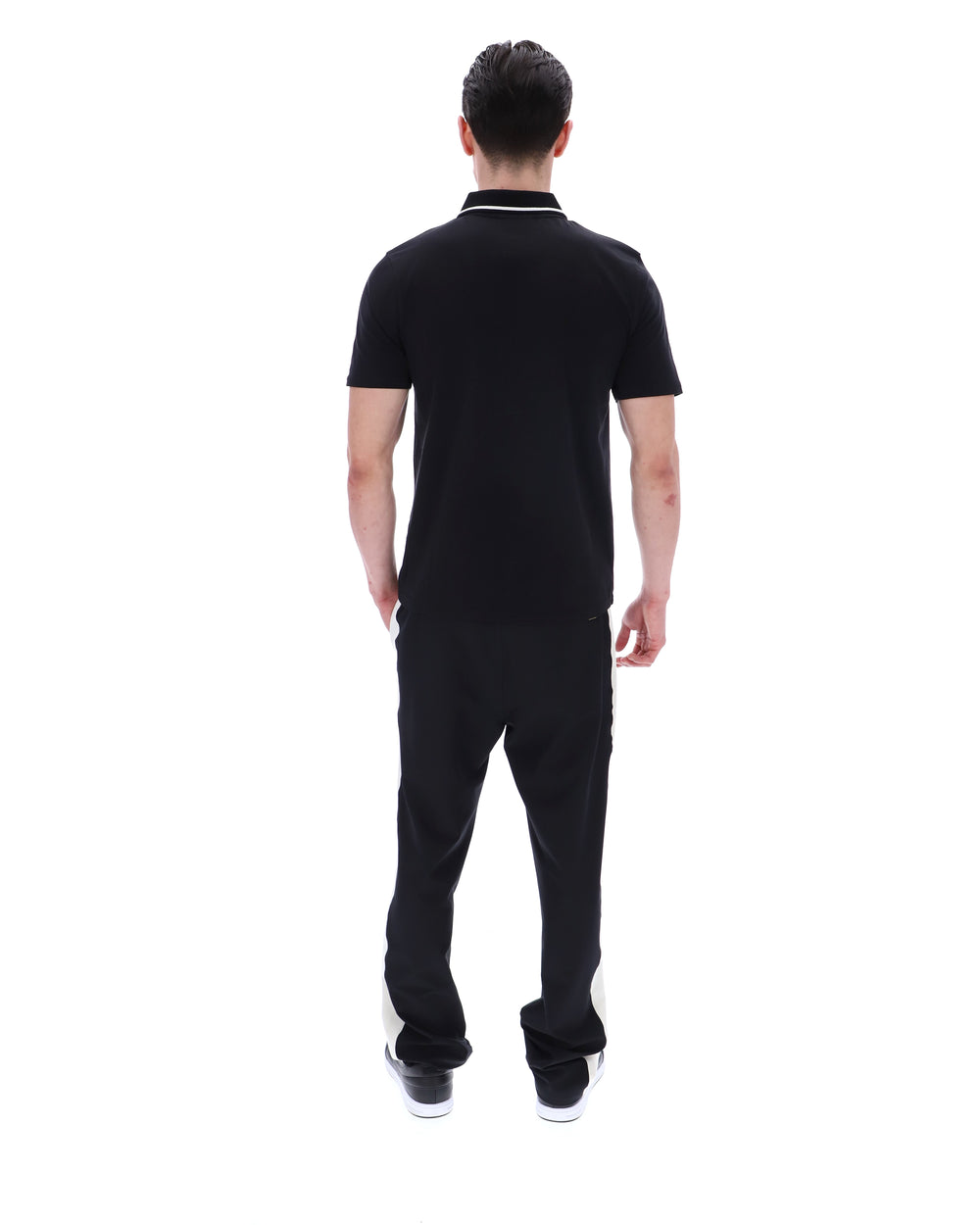 Man wearing a black polo shirt with a small logo on a white background