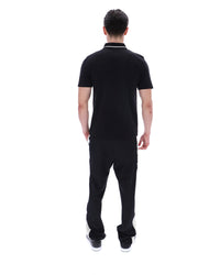 Man wearing a black polo shirt with a small logo on a white background