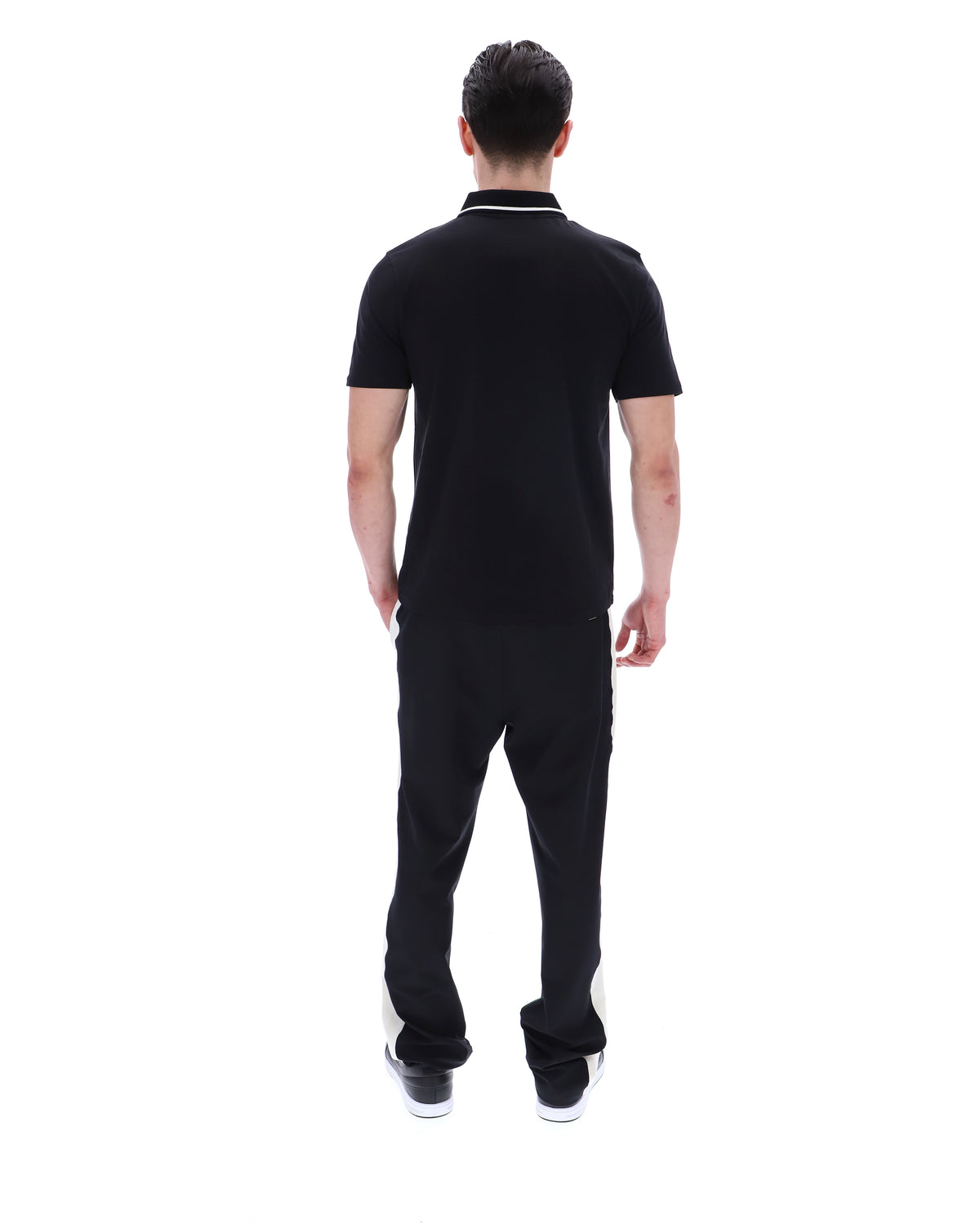 Man wearing a black polo shirt with a small logo on a white background