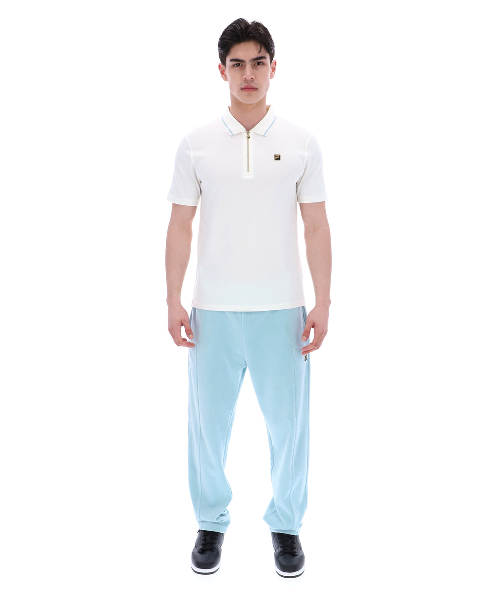 Man wearing a white polo shirt and light blue pants on a white background