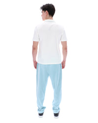 Person wearing a white polo shirt and light blue pants on a white background