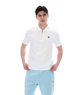 Man wearing a white polo shirt and light blue pants on a white background