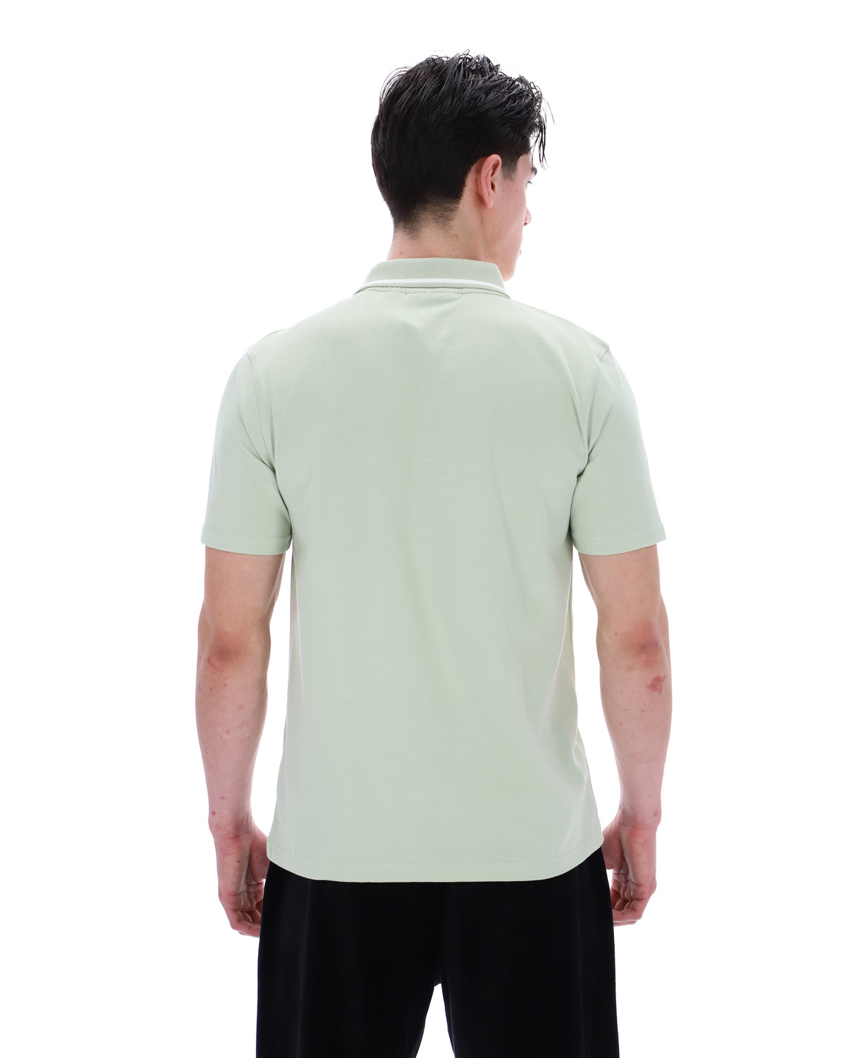 Person wearing a light green polo shirt on a white background