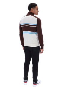 A man shown from the back wearing a brown and white striped quarter-zip pullover sweater with light blue accents, paired with black pants and white sneakers, on a solid white background.