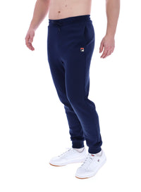 A person standing and wearing navy blue Lonny drawstring joggers with a drawstring waistband and cuffed design, featuring FILA logo branded on the waistband.