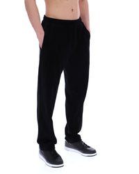 Displays the model wearing the Black 'FILA' branded Lorrie Velour Track Pant
