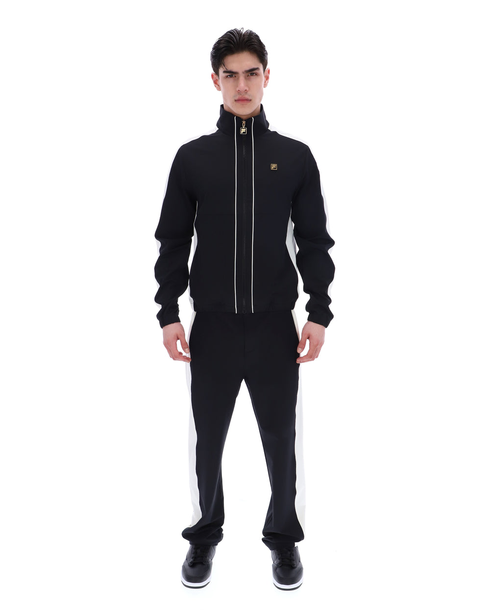 Man wearing a black tracksuit with white stripes on a white background