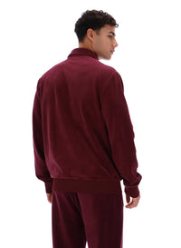Person wearing a burgundy tracksuit jacket and bottoms on a white background