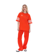 Woman wearing an Orange t-shirt with '1911' text and white stripes on sleeves, FILA logo on chest, on a white background