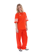Woman wearing an Orange t-shirt with '1911' text and white stripes on sleeves, FILA logo on chest, on a white background