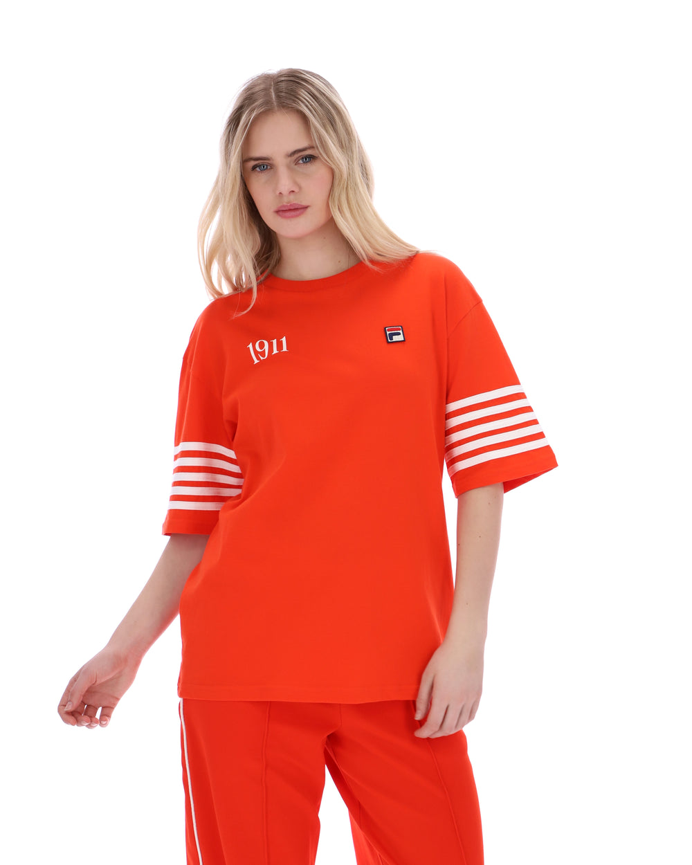 Woman wearing an Orange t-shirt with '1911' text and white stripes on sleeves, FILA logo on chest, on a white background