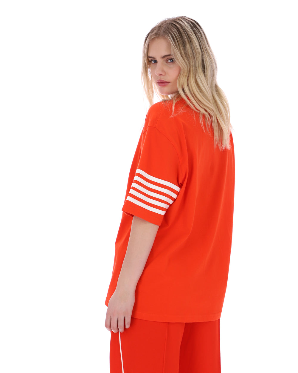 Woman wearing an orange outfit with white stripes on a white background
