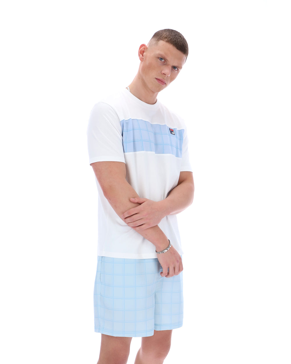 Person wearing a white t-shirt with a blue stripe and light blue shorts on a white background