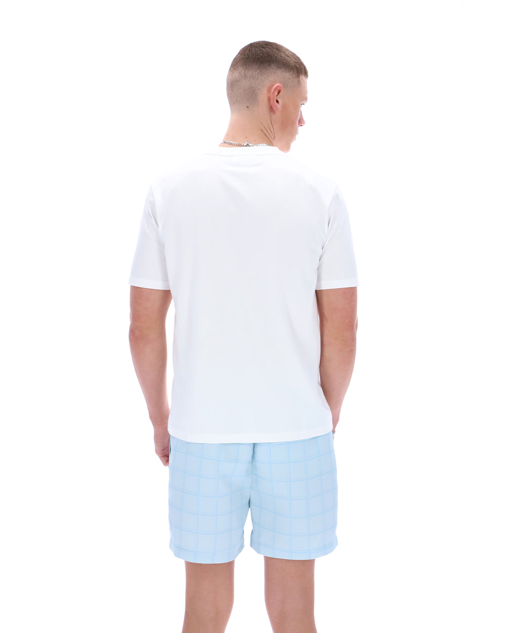 Man wearing a white polo shirt and light blue shorts on a white background