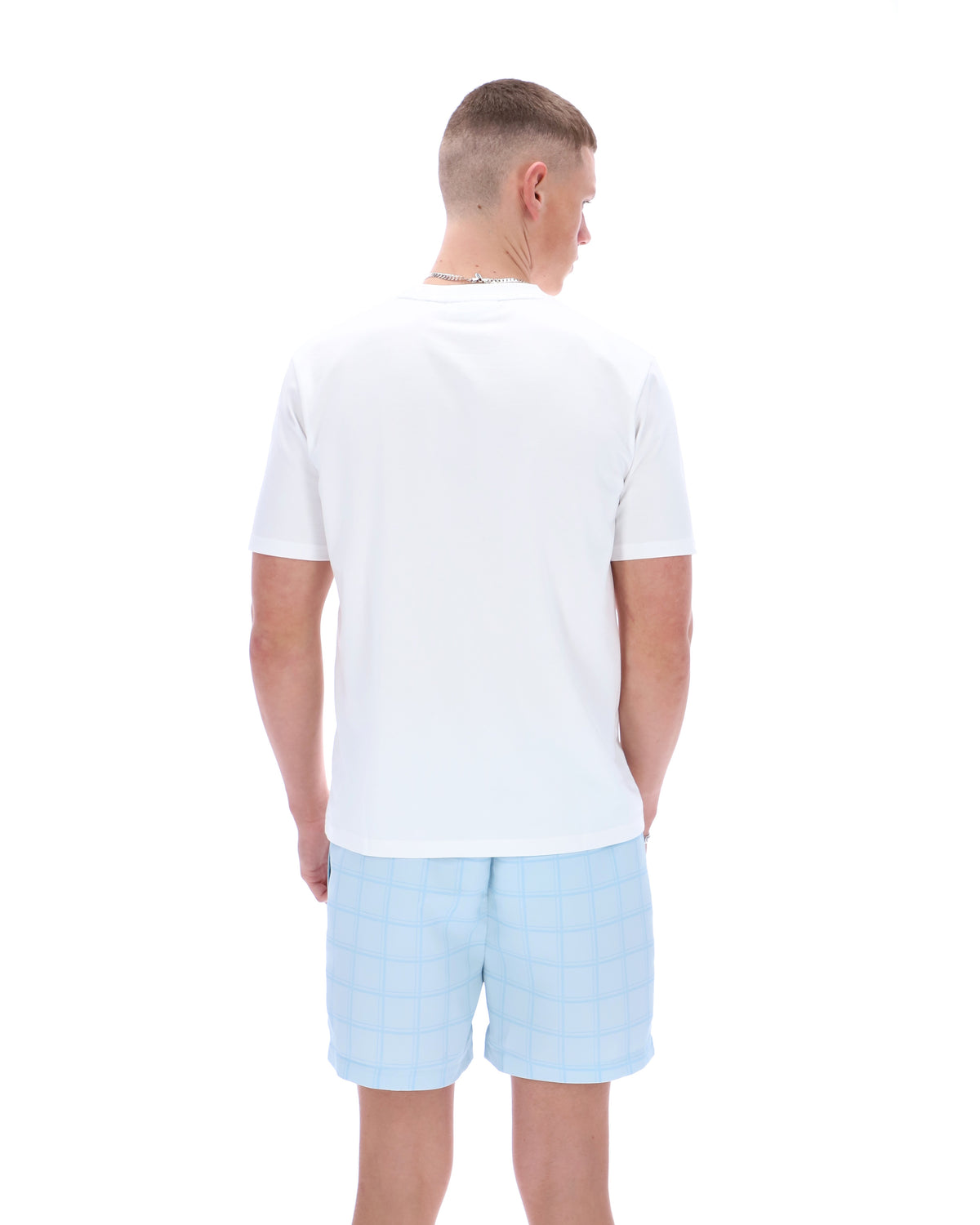 Man wearing a white polo shirt and light blue shorts on a white background