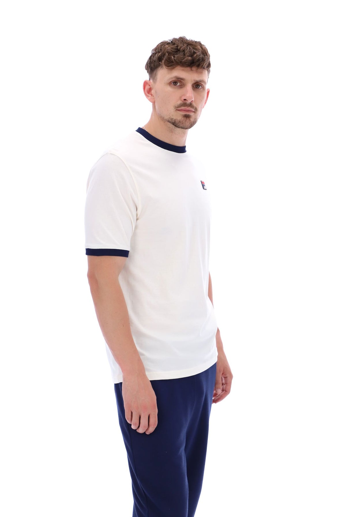 A male model wearing a white and navy ringer t-shirt with the FILA logo on the chest.