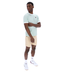 Man wearing a light blue t-shirt and beige shorts on a white background