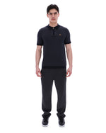 Man wearing a black outfit with a small logo on a white background