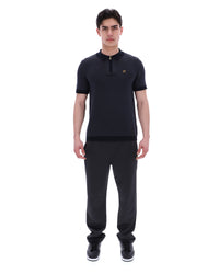 Man wearing a black outfit with a small logo on a white background