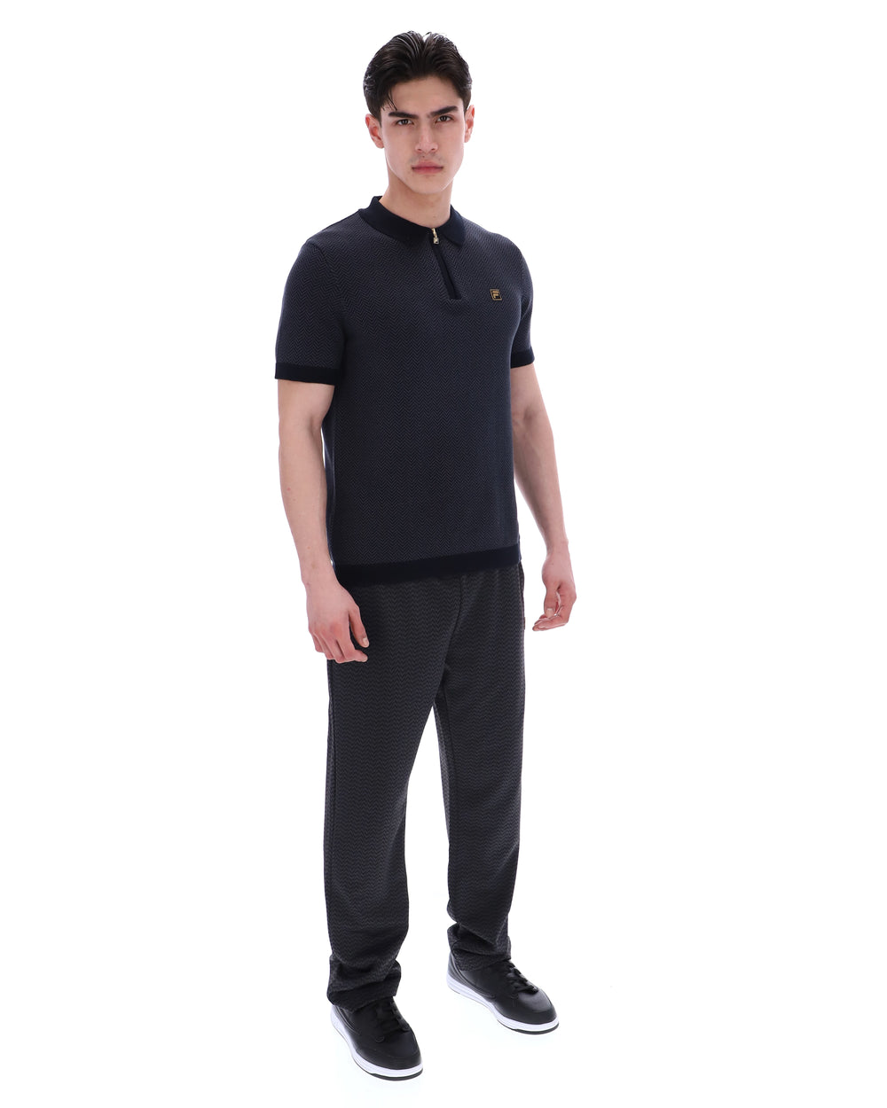 Man wearing a black polo shirt and pants on a white background