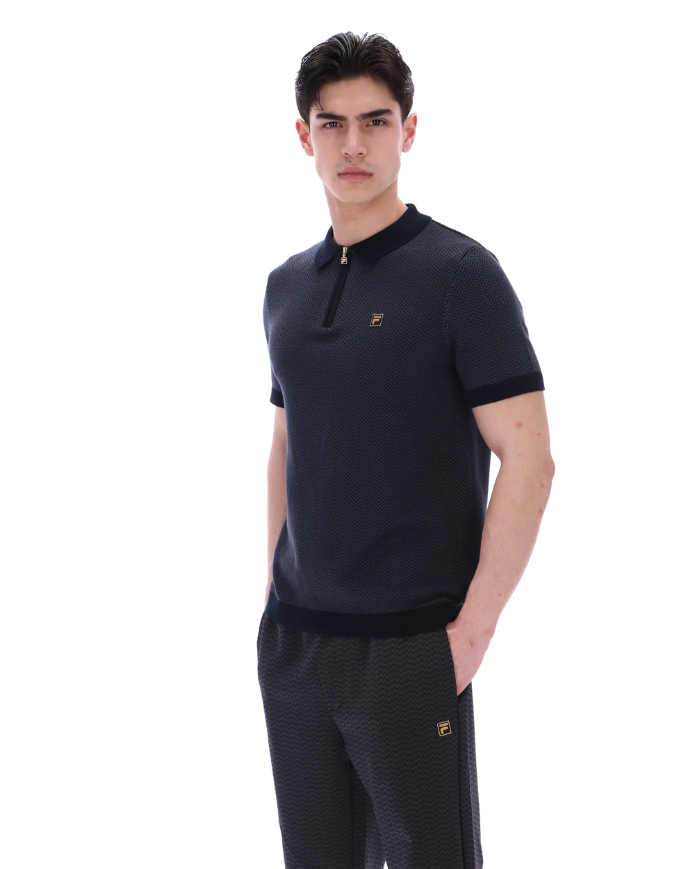 Man wearing a black polo shirt and pants with a brand logo on a white background