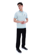 Man wearing a light blue polo shirt and black pants on a white background