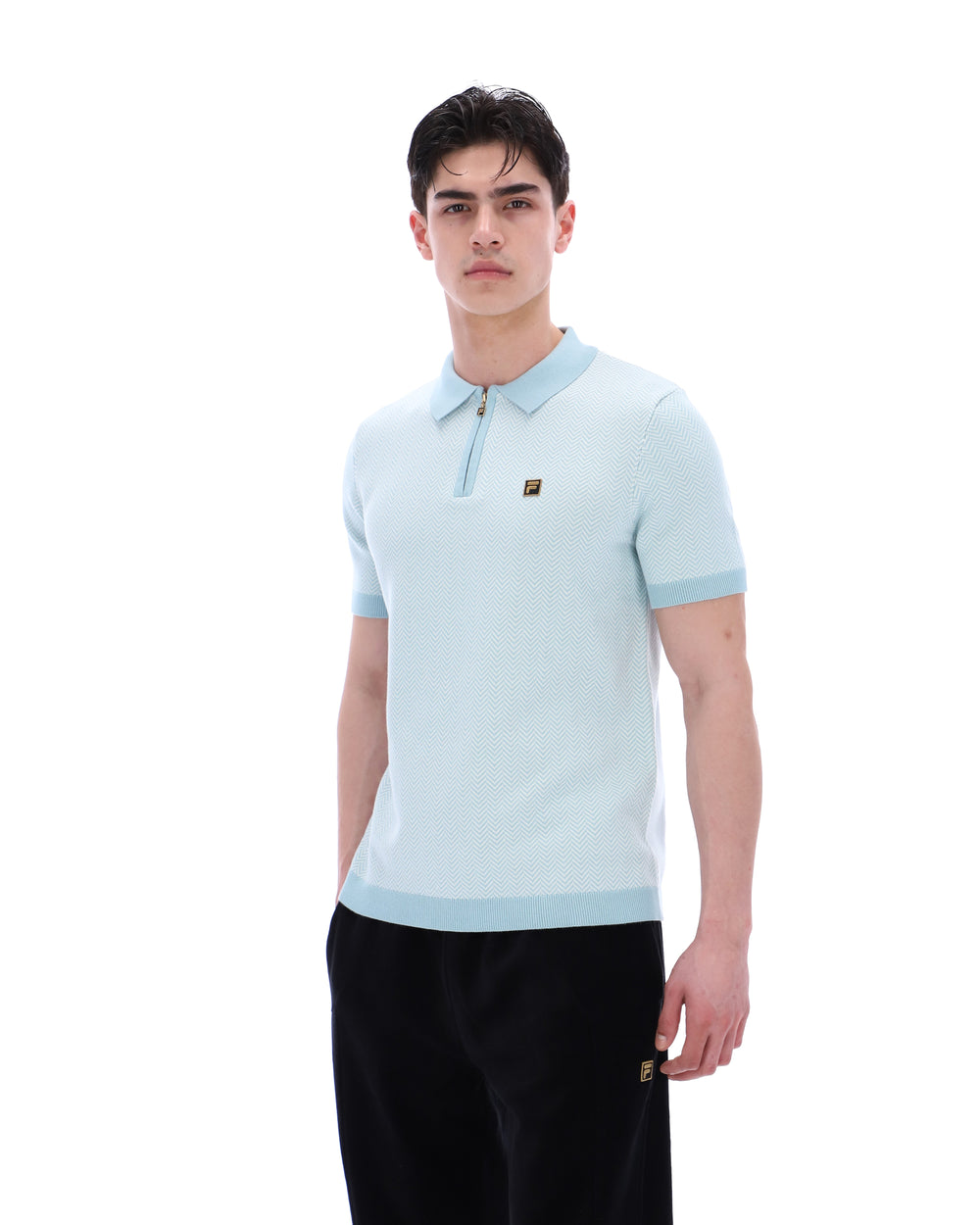 Man wearing a light blue polo shirt with a brand logo on a white background
