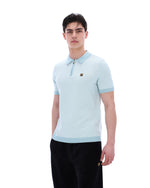 Man wearing a light blue polo shirt with a brand logo on a white background
