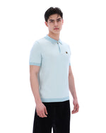 Man wearing a light blue polo shirt with a brand logo on a white background