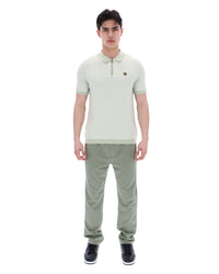 Man wearing a light green polo shirt and pants on a white background