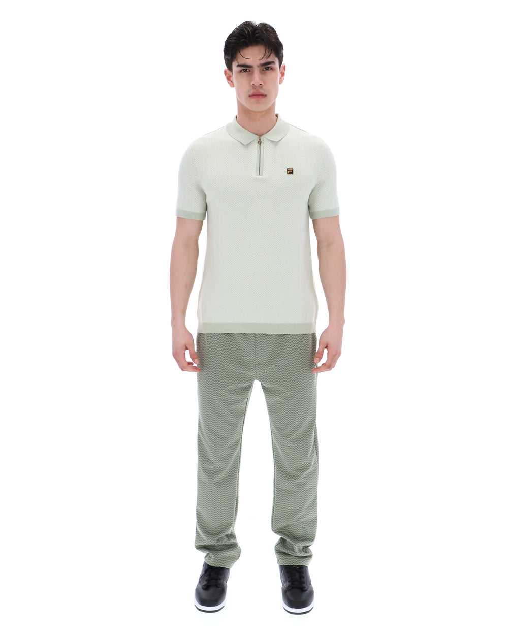 Man wearing a light green polo shirt and pants on a white background