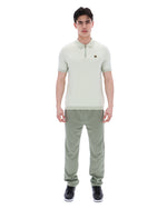 Man wearing a light green polo shirt and pants on a white background