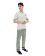 Man wearing a light green polo shirt and striped pants on a white background