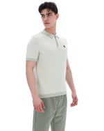 Man wearing a light green polo shirt and patterned pants on a white background