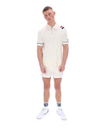 Man wearing a white polo shirt with a FILA logo on the sleeve, paired with matching shorts, on a white background