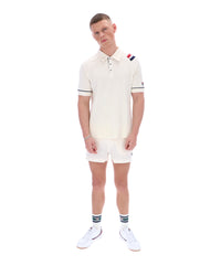 Man wearing a white polo shirt with a FILA logo on the sleeve, paired with matching shorts, on a white background