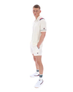 Man wearing a white polo shirt with a FILA logo on the sleeve, paired with matching shorts, on a white background