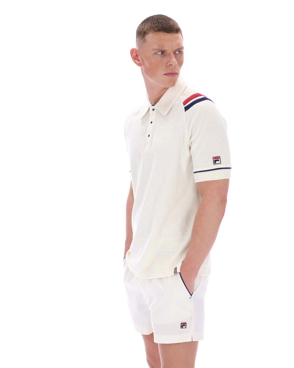 Man wearing a white polo shirt with a FILA logo on the sleeve, on a white background