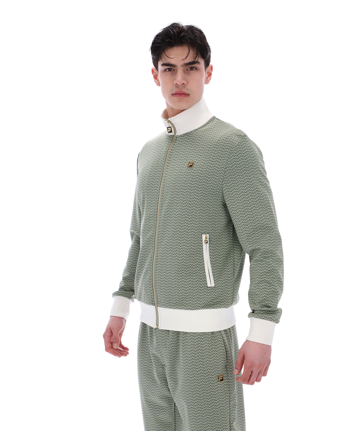 Displays a model wearing the Sea Foam 'FILA' branded Mathers Herringbone Track Top