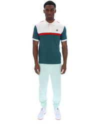 Man wearing a color-blocked polo shirt and light blue pants on a white background