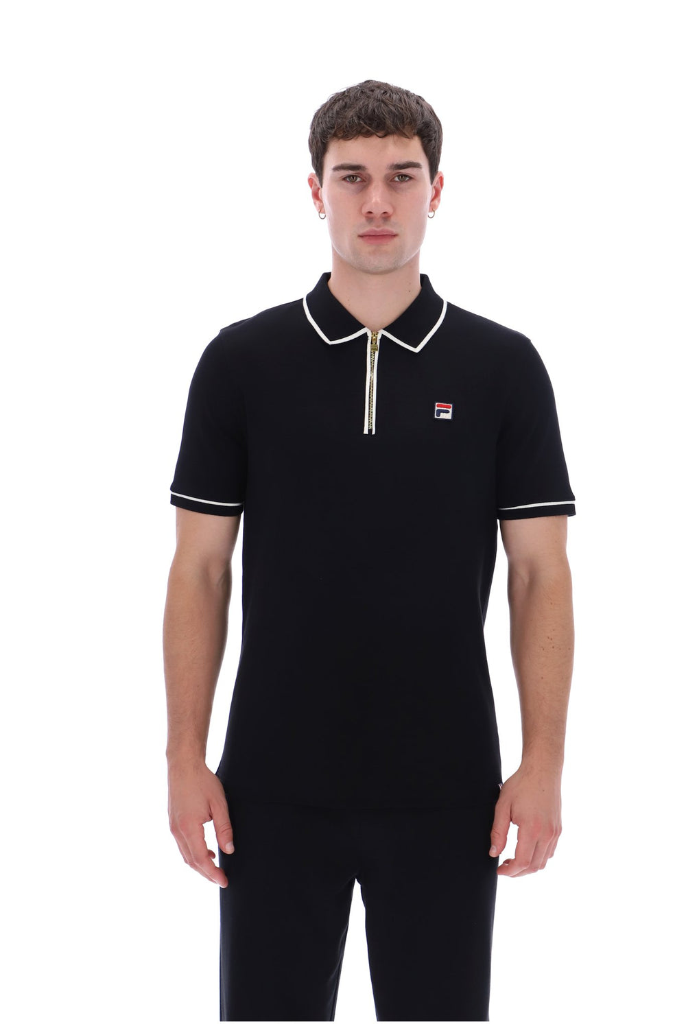A man wearing a black short-sleeve polo shirt with white trim on the collar, sleeve cuffs, and a small Fila logo on the left chest, photographed against a plain white background.