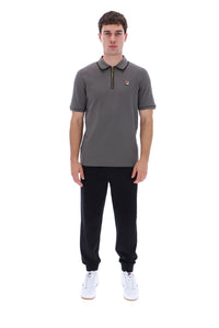 A man modeling a dark gray short-sleeve polo shirt with a half-zip collar, black jogger pants, and white sneakers against a plain white background.
