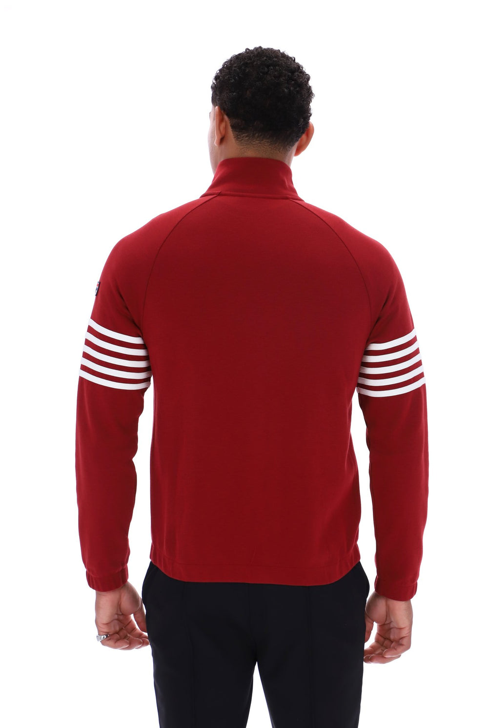 A man viewed from the back wearing a red mock-neck long-sleeve top with white stripes on the sleeves, paired with black pants, against a plain white background.