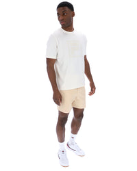 Man wearing a white t-shirt with a cream FILA logo printed on the chest on a white background.