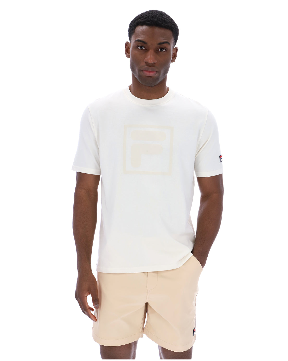 Man wearing a white t-shirt with a cream FILA logo printed on the chest and a classic FILA logo on the sleeve.