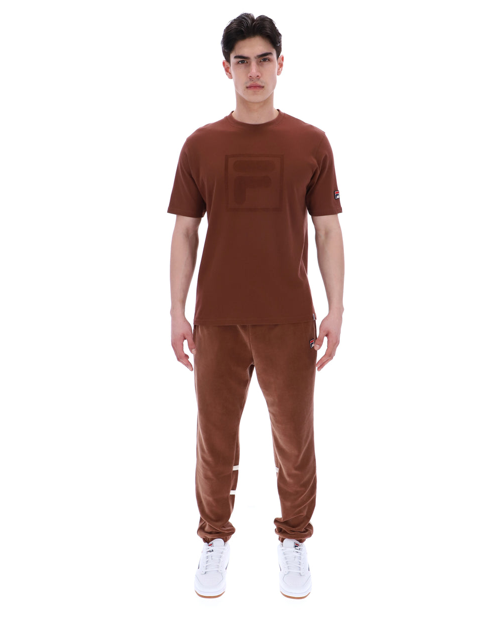 Man wearing a brown t-shirt and pants on a white background