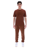 Man wearing a brown t-shirt and pants on a white background