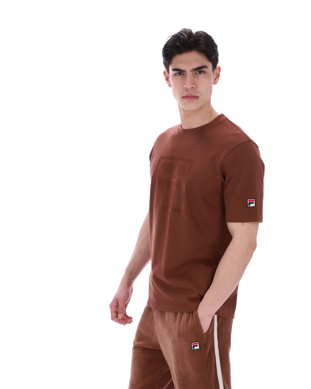 Man wearing a brown t-shirt and pants with a logo on a white background