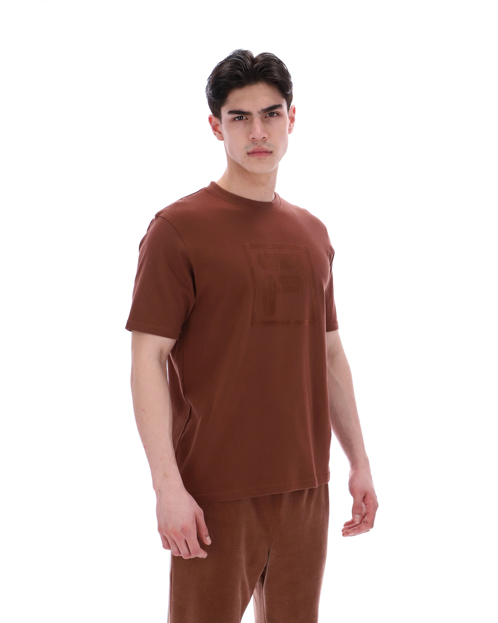 Man wearing a brown t-shirt and pants on a white background