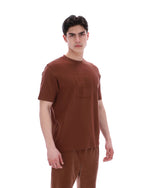 Man wearing a brown t-shirt and pants on a white background
